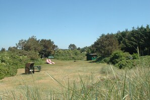 Un champ d’herbe avec une table de pique-nique, un petit abri et un toboggan rouge et blanc.