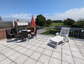 A patio with outdoor furniture, a grill, and a view of the countryside. - Haus Dorfschmiede, Whg. Ankerplatz - Haus Dorfschmiede (Alkersum)