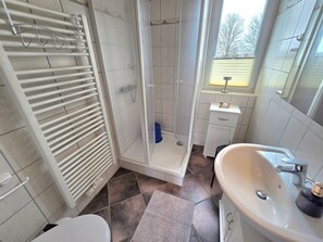 A bathroom with a shower, toilet, sink, and towel rack. - Haus Dorfschmiede, Whg. Ankerplatz - Haus Dorfschmiede (Alkersum)