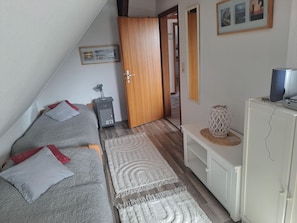 A bedroom with a bed, a desk, a wardrobe, and a television.
