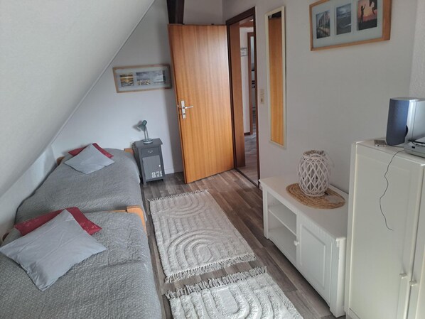 A bedroom with a bed, a desk, a wardrobe, and a television.