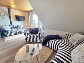 Un salon moderne avec des meubles à rayures, un téléviseur à écran plat et une grande fenêtre.