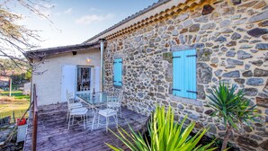 A stone house with a wooden deck, a glass table, and chairs. - Lovely home in Aubenas (Aubenas)