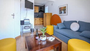 A living room with a blue sofa, yellow ottomans, a wooden coffee table, and a TV mounted on the wall. - Lovely home in Aubenas (Aubenas)