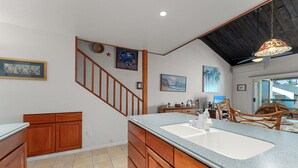 Eine Küche mit Holzausstattung, einer Granit Arbeitsplatte, einer eingebauten Spüle und einer Treppe zu einer anderen Ebene.
