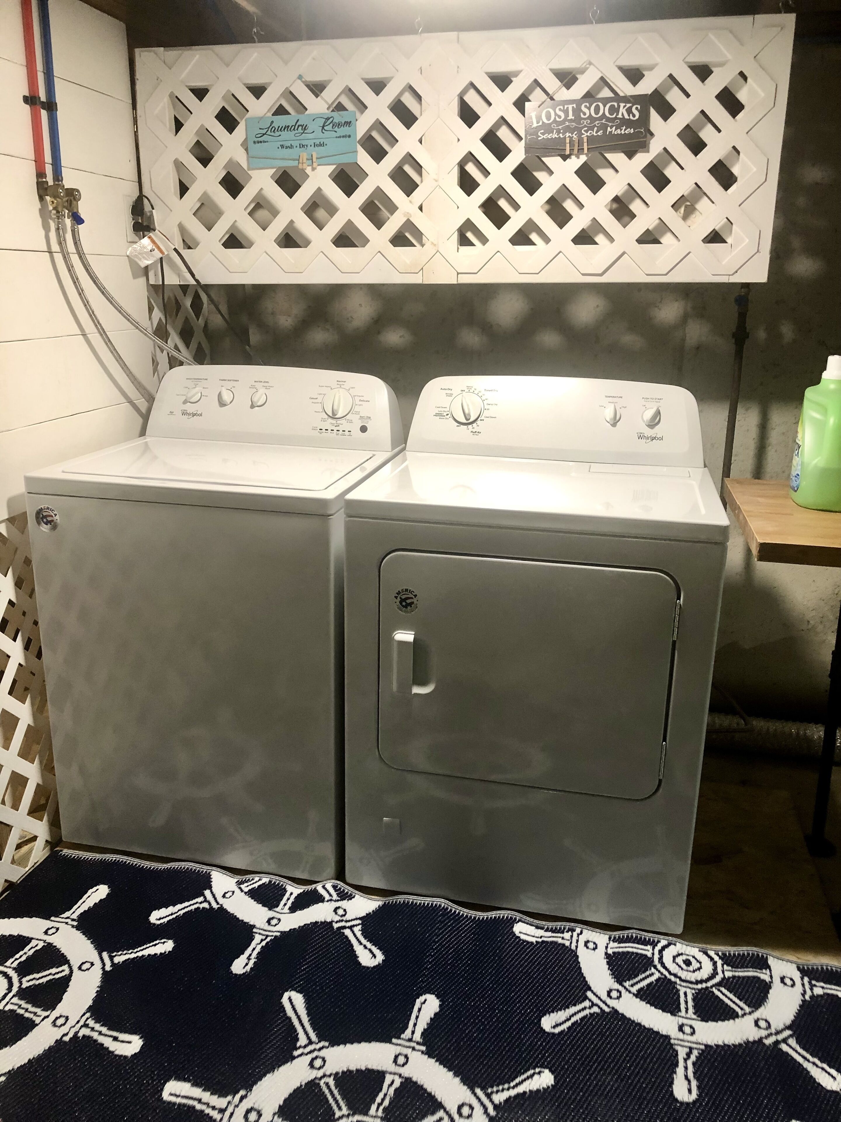 A laundry room with two Whirlpool washers, a sign for the laundry room, and a sign for lost socks.