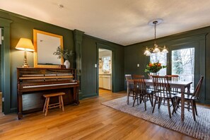 A dining area with a piano, wooden chairs, a table, and a chandelier. - The Green House - Central location PTC Trilith & Airport (Tyrone)