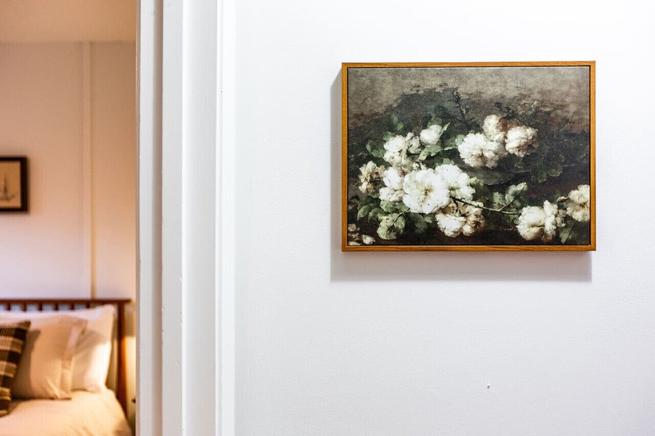 Et indrammet maleri af hvide blomster på en hvid væg.