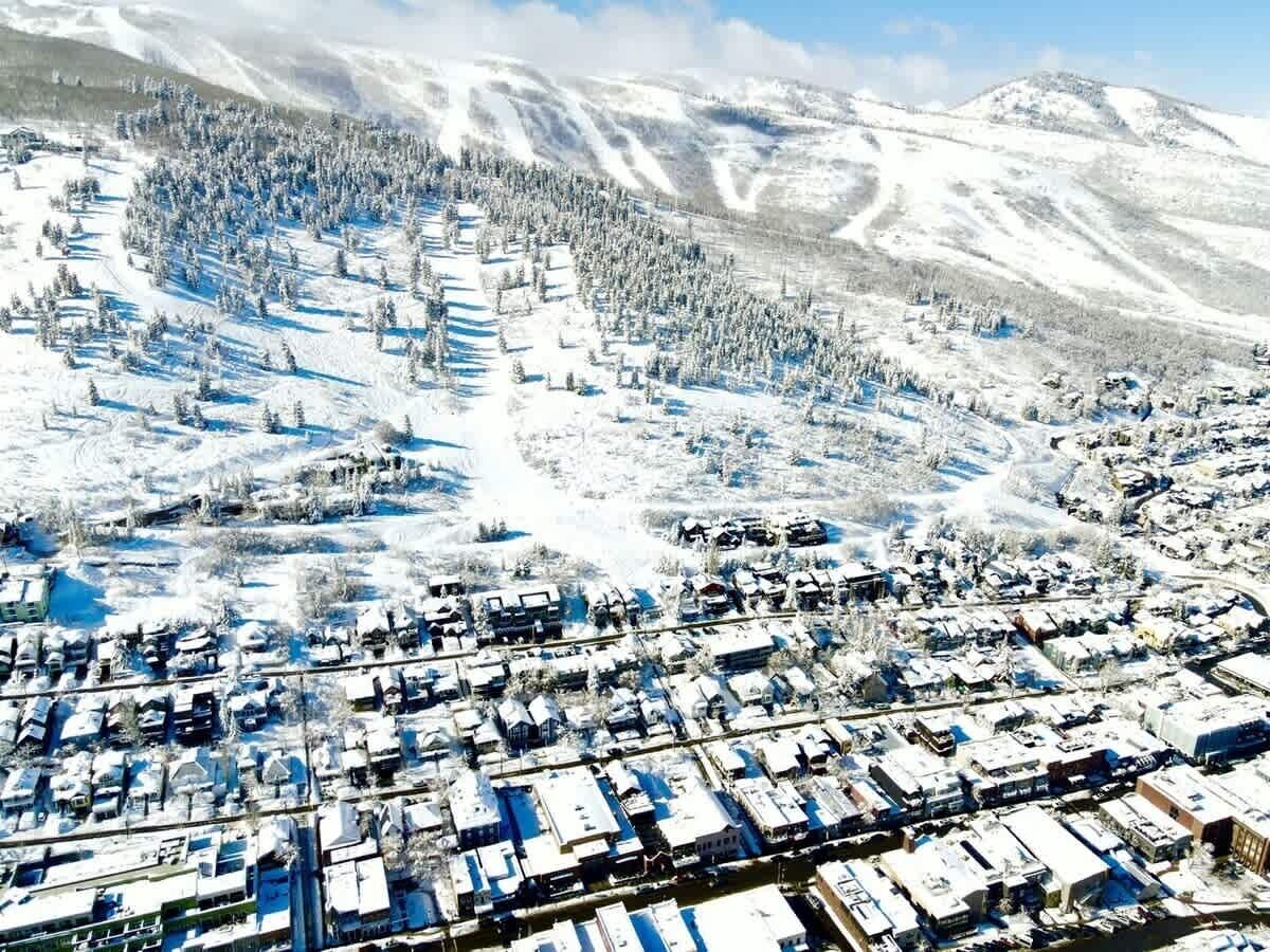 Une ville enneigée, avec des immeubles d’habitation et une chaîne de montagnes en arrière-plan.