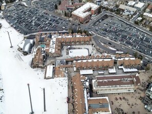 An aerial view of a commercial area with parking lots, a large building with a flat roof, and a smaller structure with a pointed roof. - Alpine Haven Retreat Ski-In Ski-Out Oasis Pool (Park City)