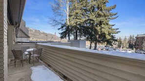 A balcony with a view of a snowy landscape, a flag, and a building in the background. - Alpine Haven Retreat Ski-In Ski-Out Oasis Pool (Park City)
