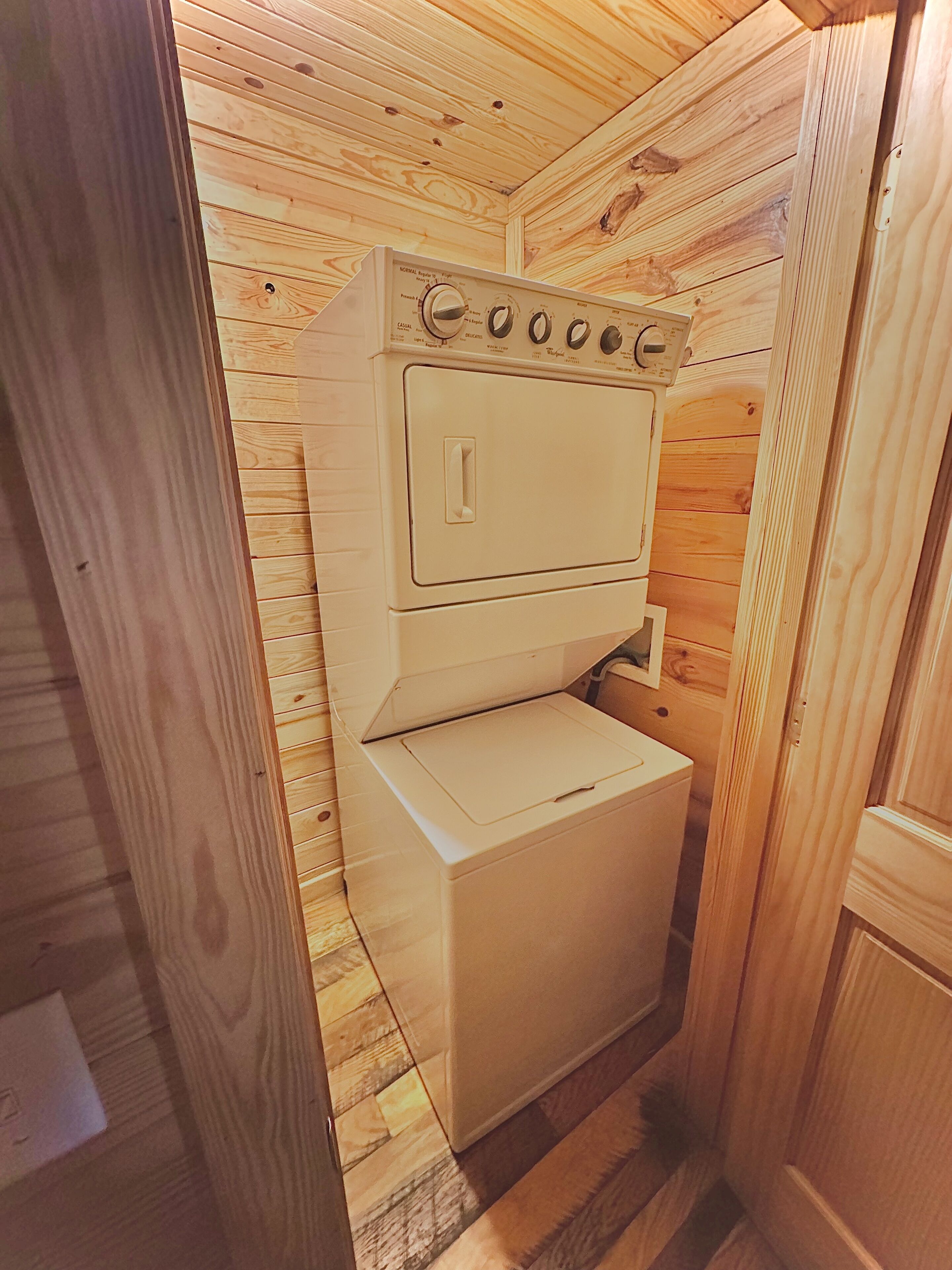 A compact, wooden-paneled laundry room with a washing machine and dryer.