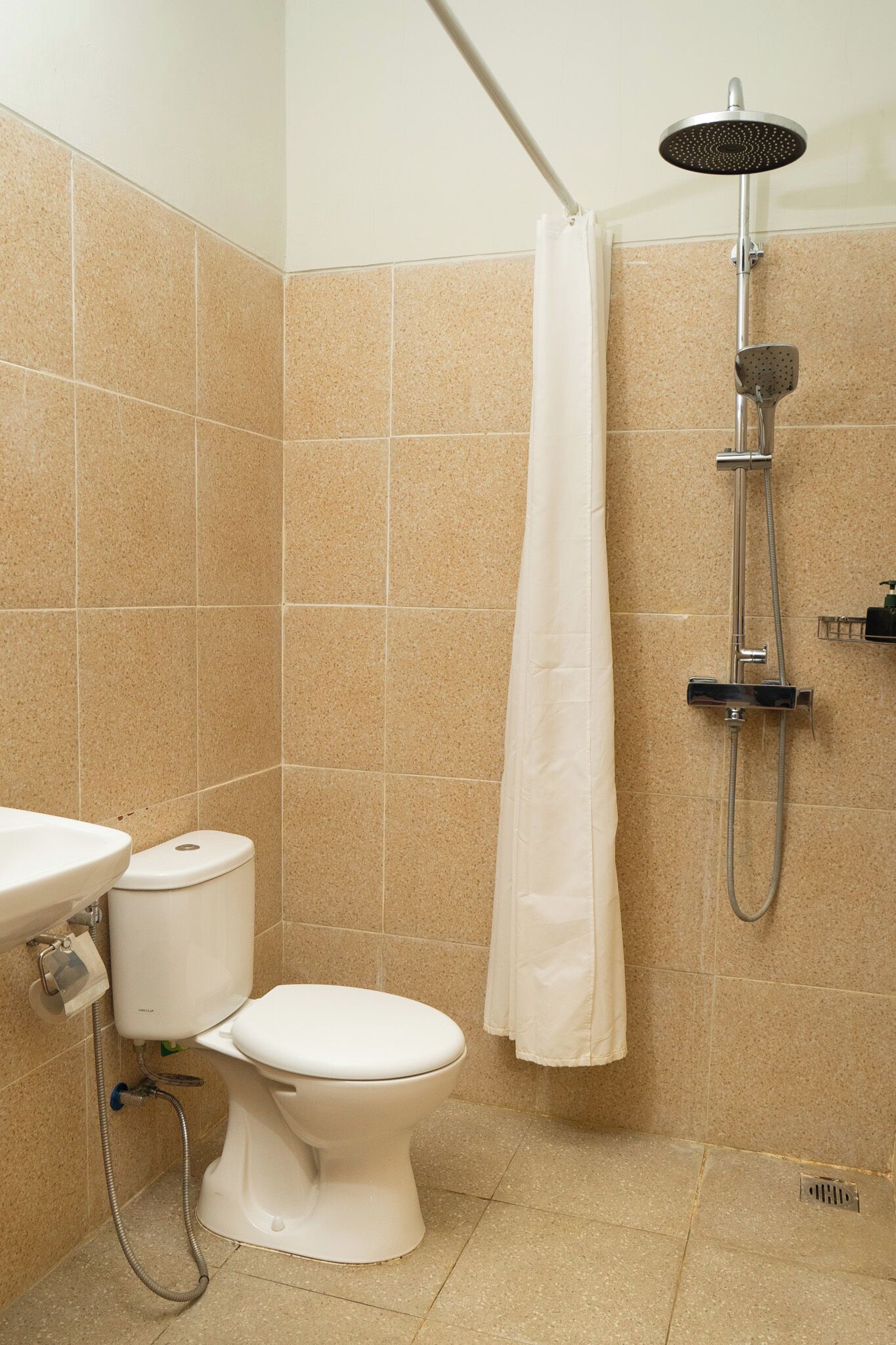 A bathroom with a toilet, sink, shower, and tiled walls.