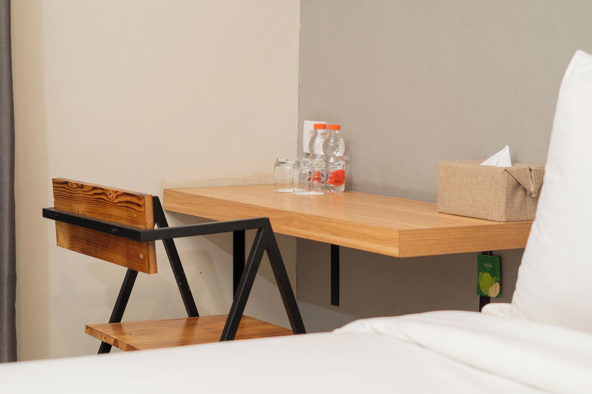 Ein kleiner Holztisch mit einem Stuhl, einer Taschentuchbox und zwei Wasserflaschen.