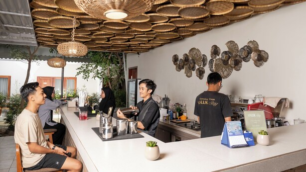 A bar area with a counter, stools, and a hanging light fixture. - Maluk Stay (Sumbawa Barat)
