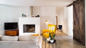 A modern living room with a fireplace, a sofa, a yellow armchair, and a television. - Wonderful private villa for 4 guests with WIFI, private pool, A/C, TV, terrace and panoramic view (Noto)