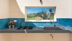 A kitchen with a window view of a rural landscape, a gas stove, and a sink.