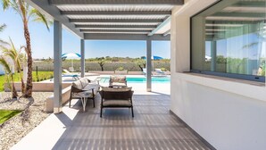 Ett takförsett utomhusområde med en pool, sittplatser och utsikt över landskapet.