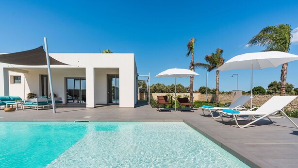 A modern pool area with clear blue water, sun loungers, and umbrellas. - Stunning private villa for 7 people with A/C, WIFI, private pool, TV, patio and panoramic view (Noto)