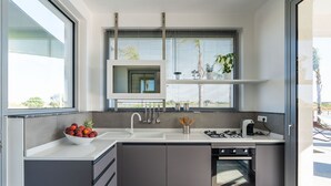 A modern kitchen with a built-in oven, a sink, and a window with blinds. - Stunning private villa for 7 people with A/C, WIFI, private pool, TV, patio and panoramic view (Noto)