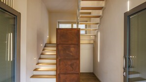 A modern staircase with wooden steps and a central metal column, flanked by glass doors with metal handles.