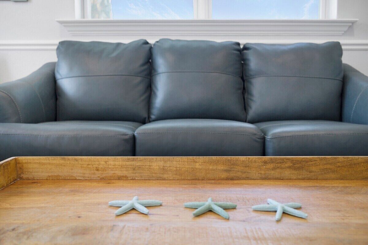 A grey leather sofa with three starfish on a wooden tray.