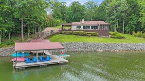 A lakeside cabin with a dock, a covered seating area, and a well-maintained lawn. - Beautiful Waterfront Home w Hot Tub and great entertaining options! (Mooresville)