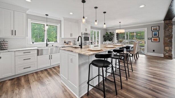 A modern kitchen with white cabinetry, a central island with bar stools, and pendant lighting. - Beautiful Waterfront Home w Hot Tub and great entertaining options! (Mooresville)