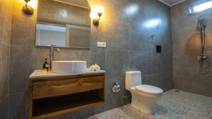 A bathroom with a sink, mirror, toilet, and shower. - The Peacock Inn Ubud (Ubud)