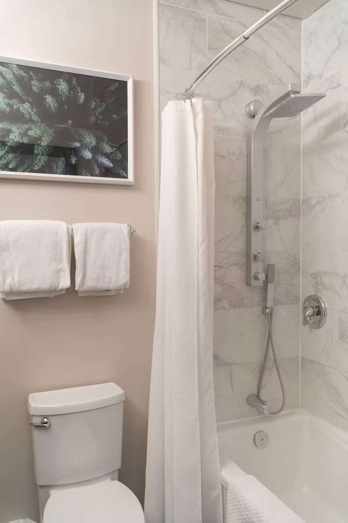 Une salle de bain moderne avec une douche, des toilettes et deux serviettes accrochées au mur.