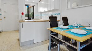 A modern kitchen with white cabinets, a wooden countertop, and a dining area with a table set for two. - Adelfas 14 - Beach, Terrace, Pool, 2 Bedrooms (Torremolinos)