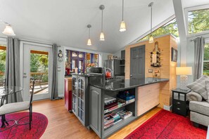 A modern kitchen with a central island, built-in appliances, and a dining area with a glass table and chairs. - Charming 2BR home with peaceful views, steps from downtown Highlands. (Highlands)