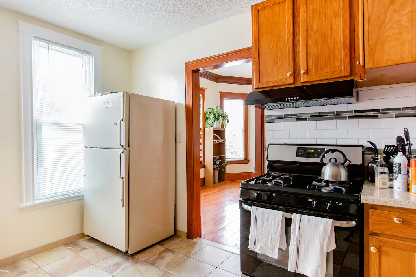 Une cuisine équipée d’un réfrigérateur, d’une cuisinière, de meubles de rangement en bois et d’une fenêtre.