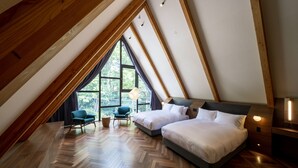 Une chambre avec deux lits, une chaise, une lampe et une grande fenêtre.