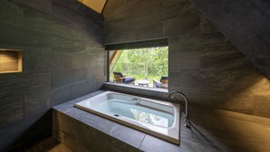 Une salle de bain moderne avec une baignoire sur pieds, une fenêtre donnant sur un jardin et une étagère intégrée.