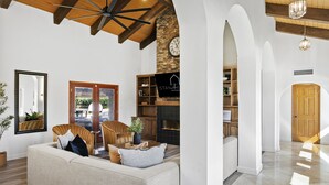 Uma sala de estar espaçosa com um sofá grande, vigas de madeira no teto, lareira de pedra e uma televisão.