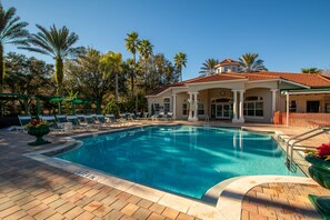 Une piscine avec des chaises longues et des palmiers.