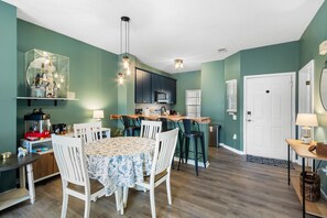 Une cuisine moderne avec des meubles de couleur sombre, un îlot central et un coin repas comprenant une table et des chaises.