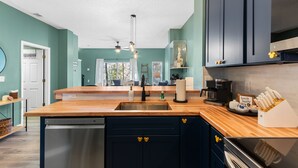 Una cocina moderna con encimera de madera, armarios oscuros y lavavajillas.