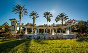 A fountain with multiple water jets, surrounded by a white archway with the words "EMERALD ISLAND" above it.