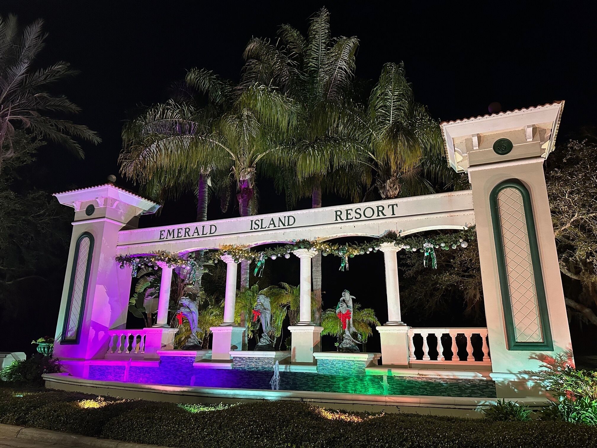 A grand entrance with a sign reading "Emerald Island Resort" and a decorative fountain.