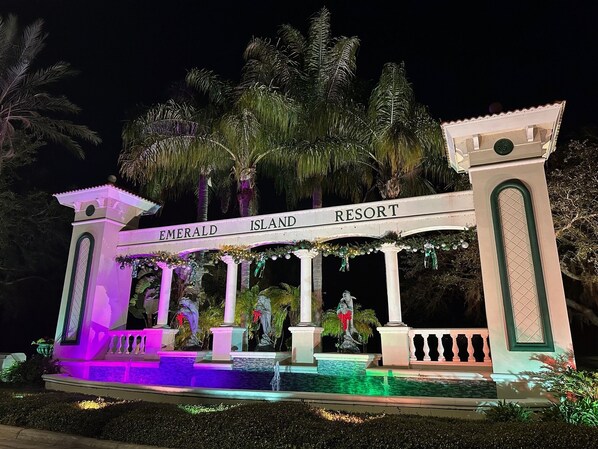 A grand entrance with a sign reading "Emerald Island Resort" and a decorative fountain.
