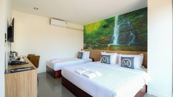 A hotel room with two beds, a desk, a chair, a TV, and a large painting of a waterfall.