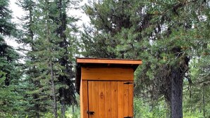 A wooden shed with a door and a small step leading up to it, surrounded by dense forest. - Glamping tent 1, remote with Glacier Park Mountain views. 5mins from Polebridge  (Polebridge)