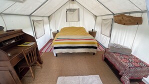A tent with a bed, a desk, and a small table. - Glamping tent 1, remote with Glacier Park Mountain views. 5mins from Polebridge  (Polebridge)