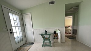 A hallway with a glass-top table, a patterned rug, and a door with frosted glass panels.