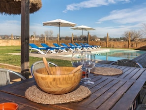 A poolside area with wooden tables, lounge chairs, and umbrellas.