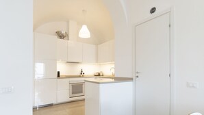 Una cocina moderna con armarios blancos, horno empotrado y una lámpara colgante.