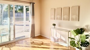 Una habitación con puerta de vidrio corredera, una mesita consola blanca con una planta y paneles decorativos en la pared.