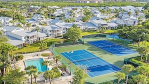 Ein Wohngebiet mit mehreren Häusern, einem Tennisplatz und einem Schwimmbad.